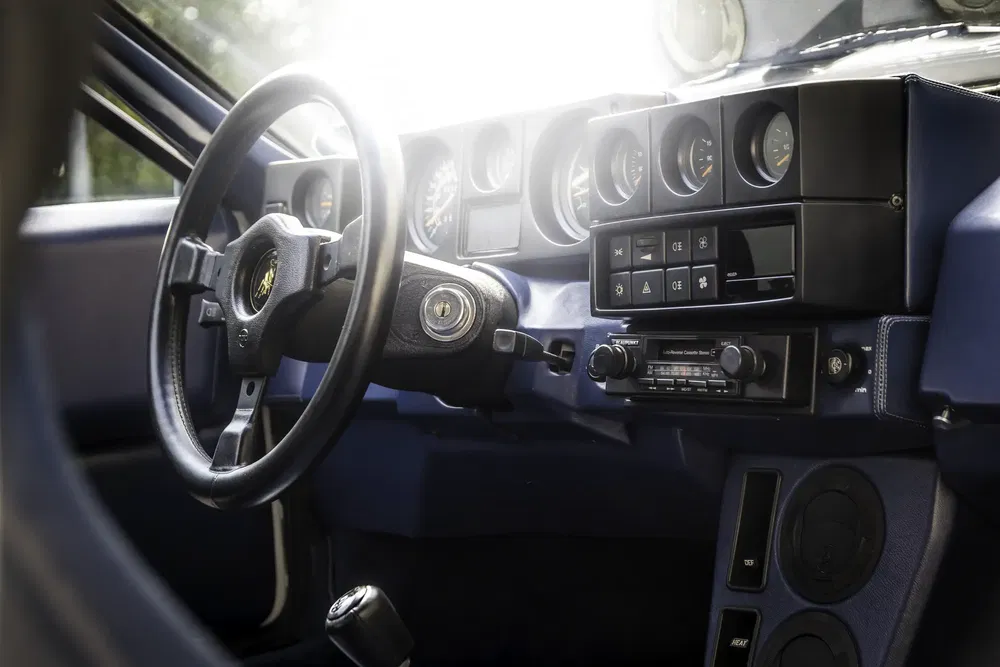 Tableau de bord de voiture vintage avec volant sport et équipements analogiques.