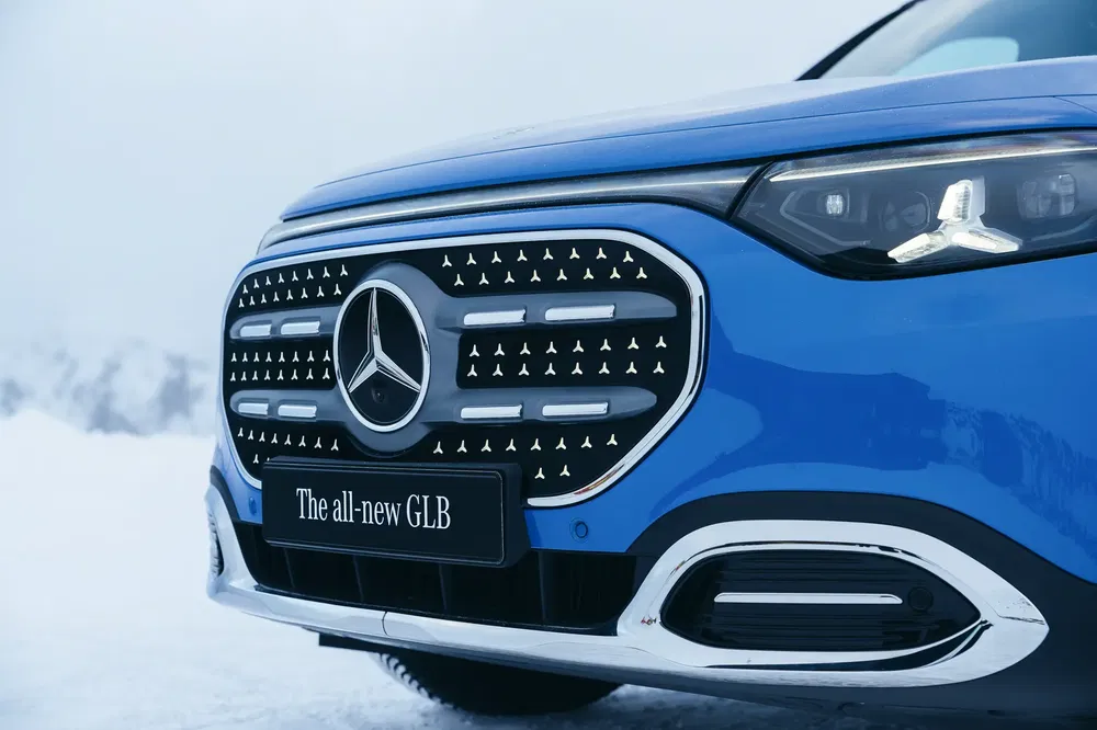Mercedes-Benz GLB bleu sur neige, grille avant moderne et phares distinctifs.