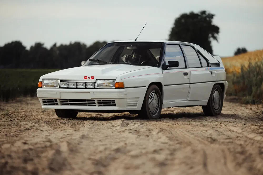 Witte Citroën BX Sport op zanderig terrein, een icoon van de jaren 80 auto's.