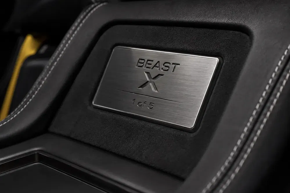 Genummerde plaat Beast X op een zwart lederen stoel met witte stiksels.