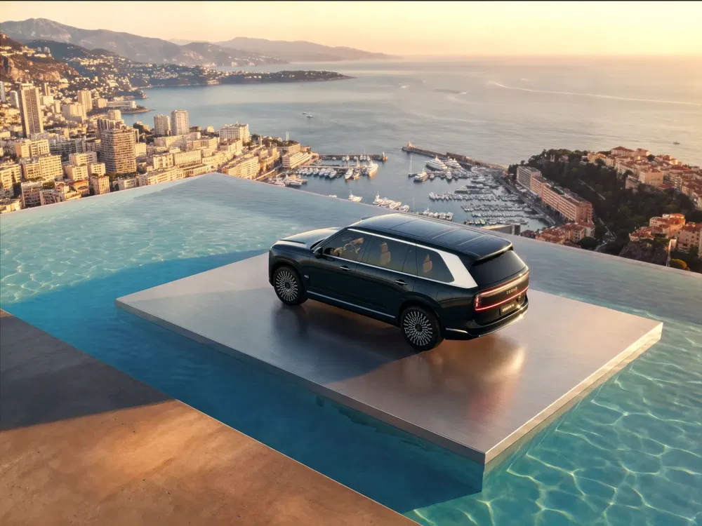 SUV luxueux sur plateforme au-dessus de piscine, vue sur ville côtière panoramique au coucher du soleil.