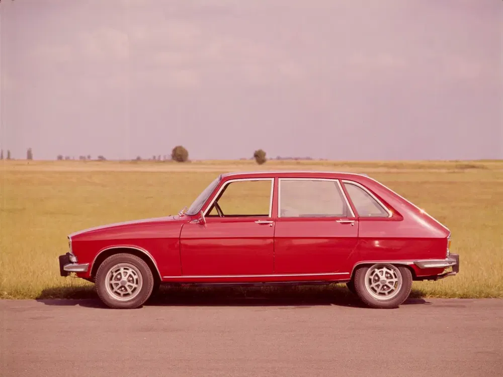 Voiture classique rouge sur une route de campagne, modèle Renault 16 des années 1960.