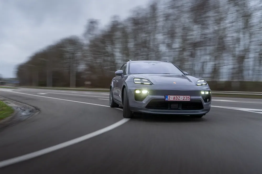Voiture Porsche sur l'autoroute avec phares allumés, vitesse et route sinueuse.