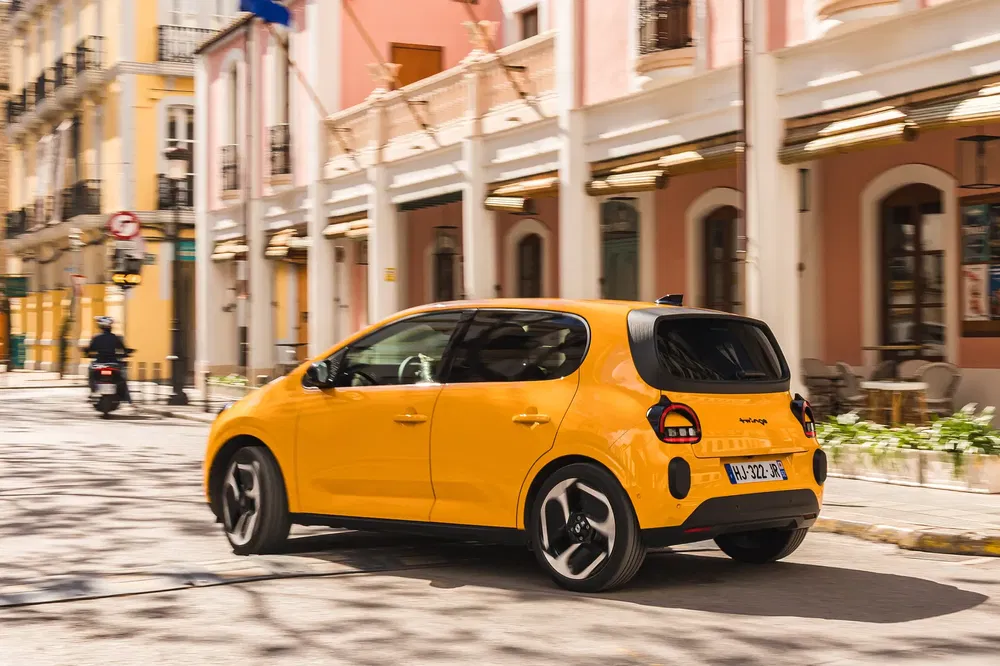 Gele Volkswagen ID.2all rijdt in stad met historische gebouwen op achtergrond.