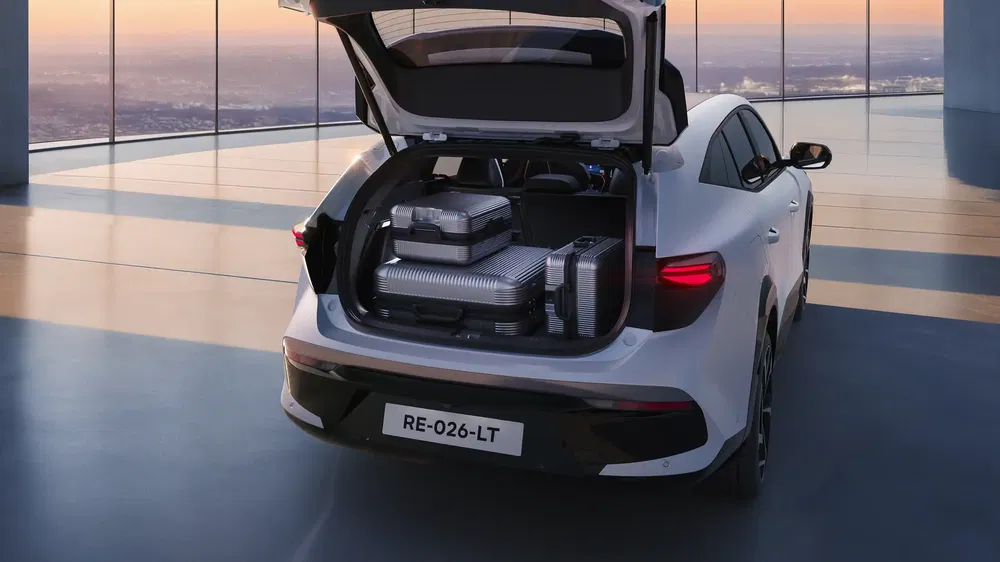 Coffre de voiture électrique Renault chargé de valises dans un parking moderne au coucher du soleil.