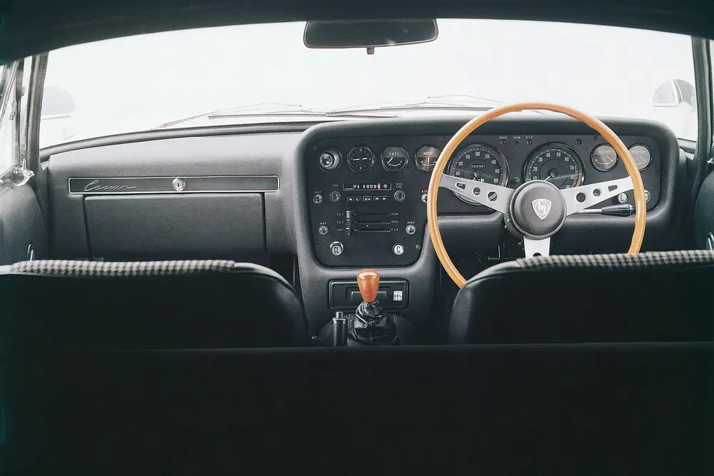 Intérieur vintage d'une voiture classique avec volant en bois et tableau de bord rétro.