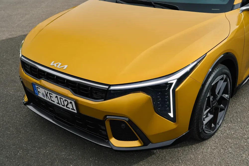 Kia jaune, calandre dynamique et feux LED avant angulaires, plaque immatriculation visible.