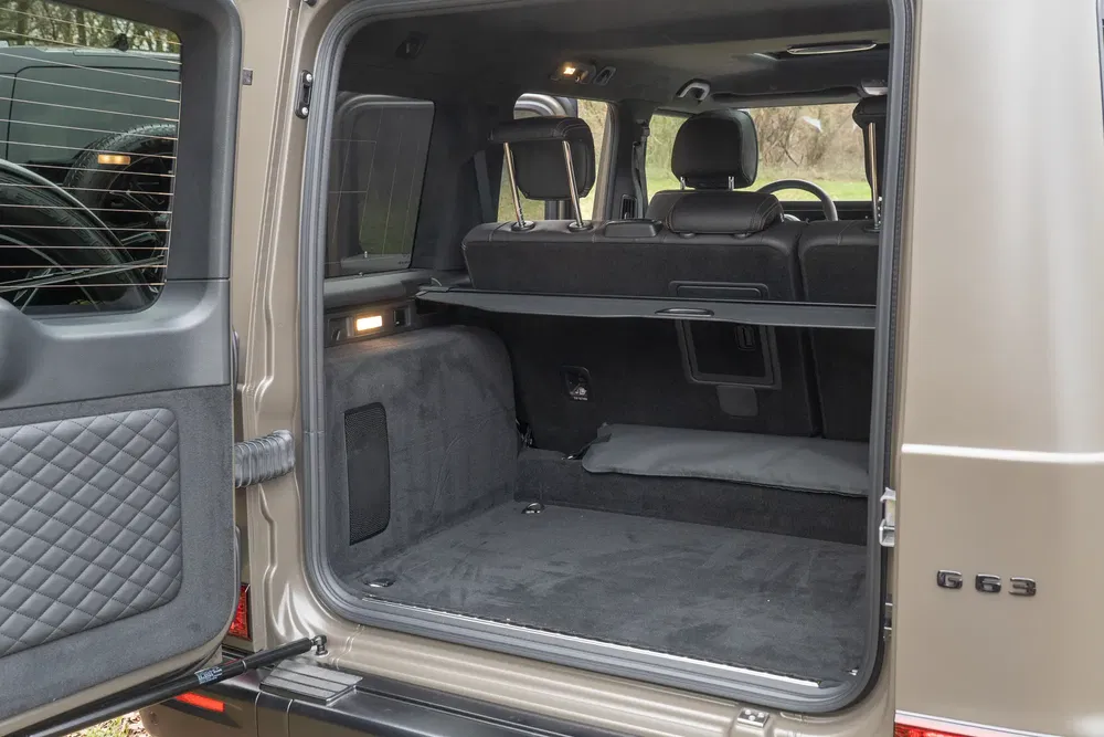 Coffre du Mercedes-Benz G63 AMG espaçieux, portes ouvertes, intérieur élégant et pratique.