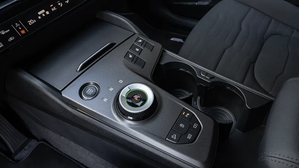 Console centrale de voiture moderne avec commandes digitales et porte-gobelet.