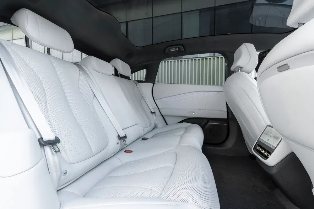 Intérieur spacieux de voiture avec sièges arrière en cuir blanc et toit panoramique en verre.