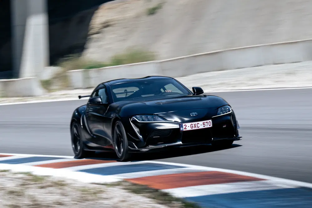 Zwarte Toyota Supra op circuit, dynamisch rijdend met indrukwekkende snelheid.