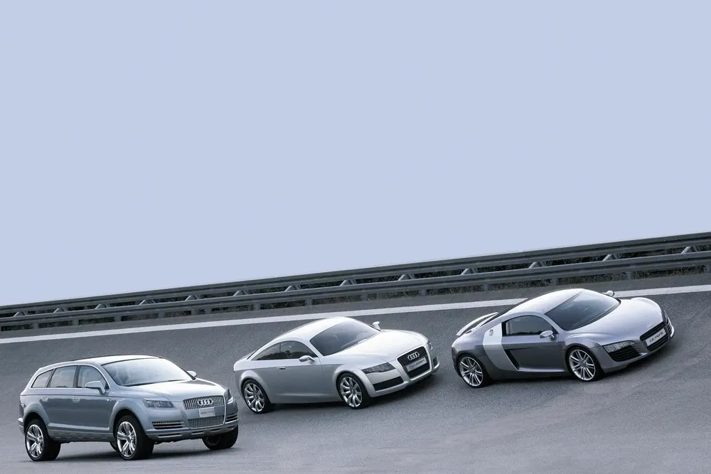 Trois voitures Audi sur une piste inclinée: Q7, TT, R8 en alignement.