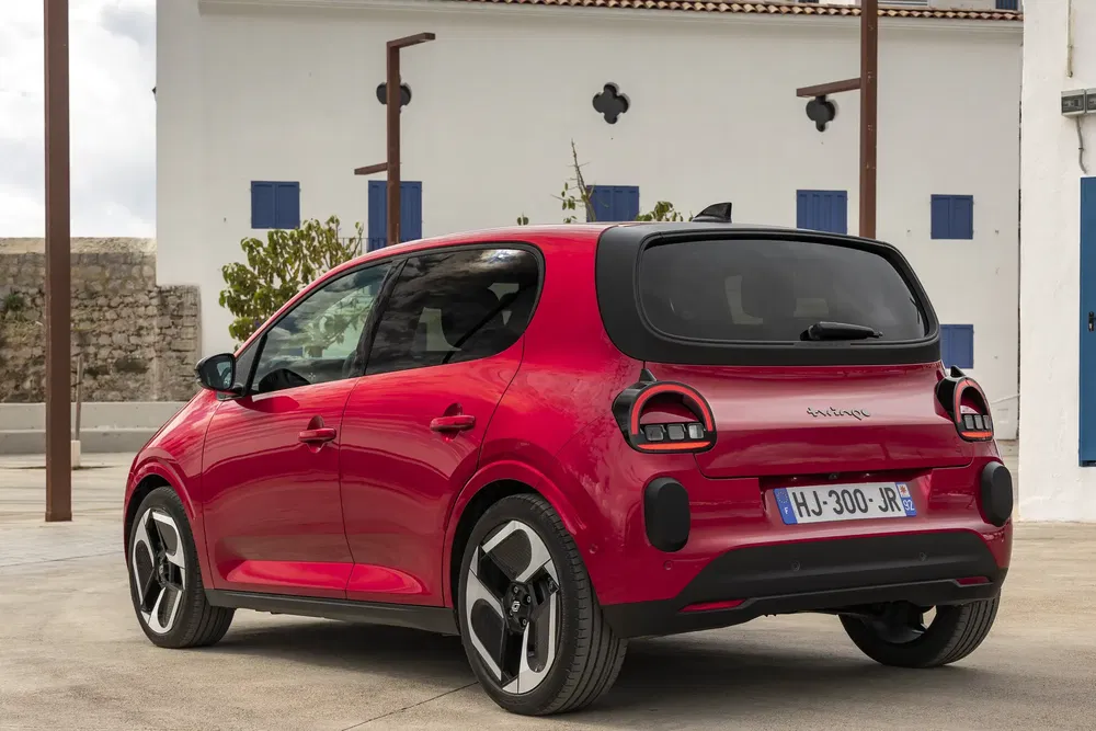 Renault Twingo rouge garée devant un bâtiment blanc, design compact et moderne.