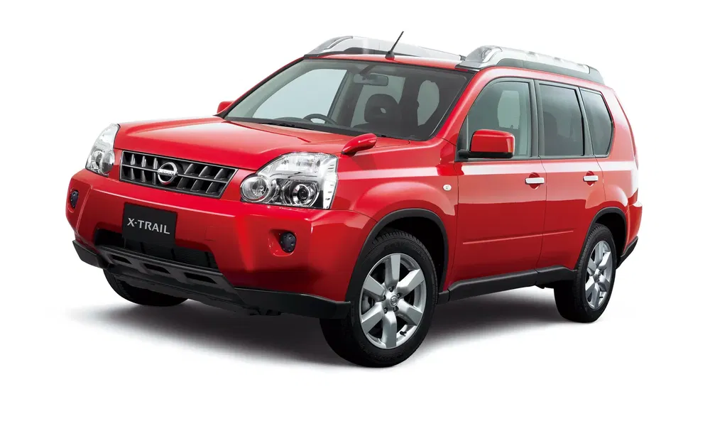 Nissan X-Trail rouge, SUV spacieux avec barres de toit argentées et jantes en alliage.