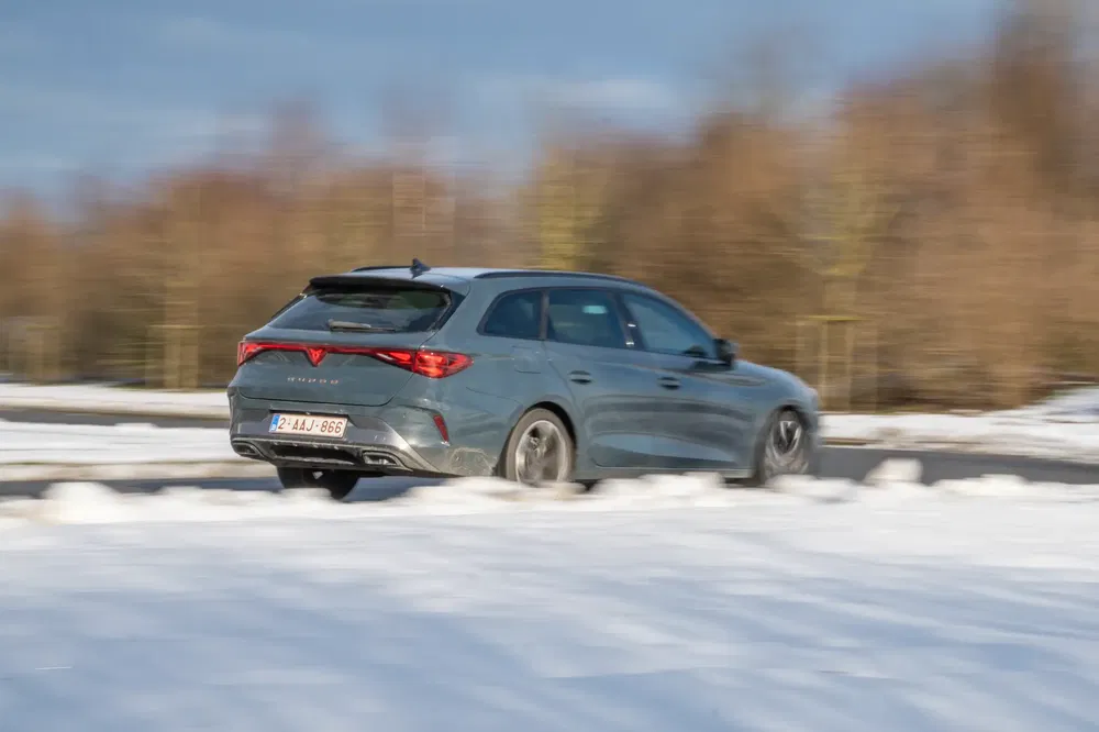 Cupra León stationwagen rijdt op besneeuwde weg, dynamische winterse sfeer.
