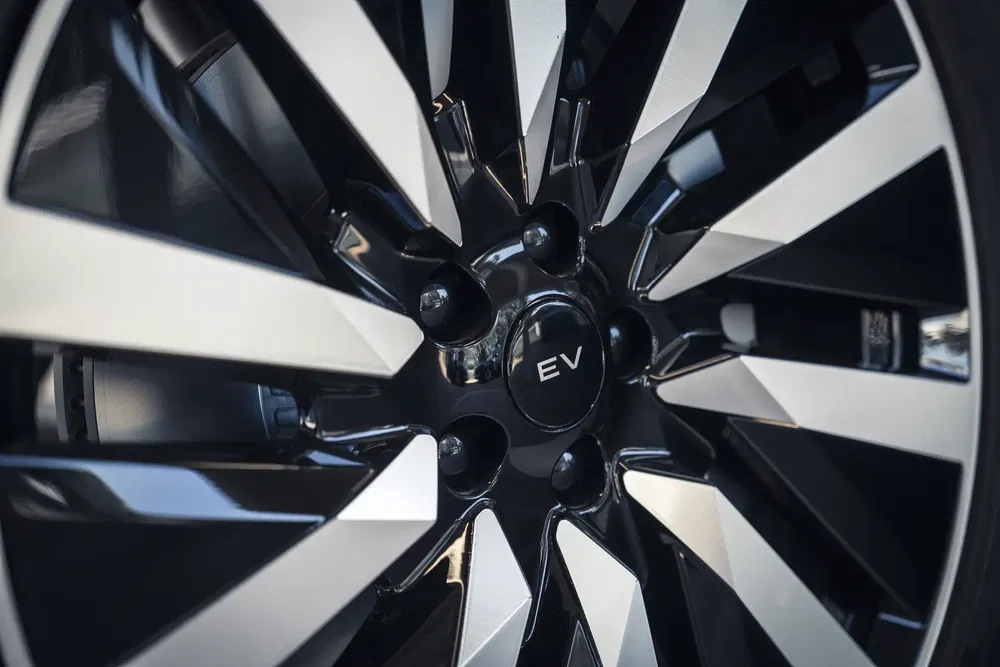 Gros plan sur une jante de voiture électrique, design moderne à rayons noirs et argentés.
