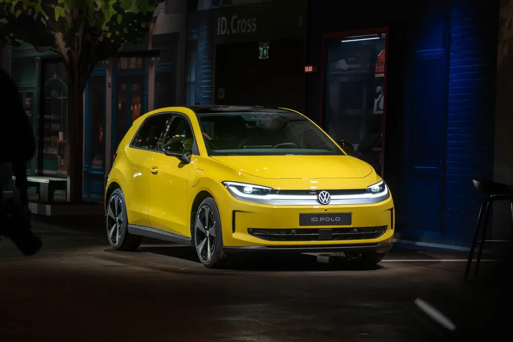 Volkswagen ID.Polo jaune vif dans un environnement urbain moderne, éclairage accentuant ses lignes élégantes.