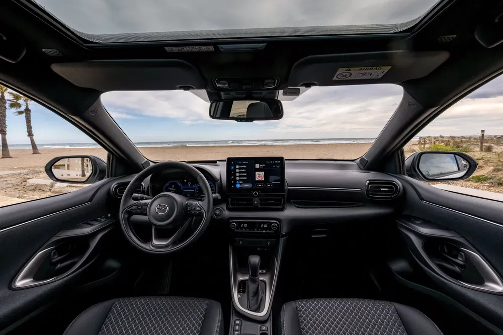 Moderne interieur van een Mazda CX-30 met panoramisch uitzicht op het strand.
