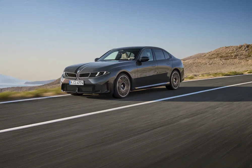 BMW Série 5 en route désertique, design moderne et élégant, ciel clair en arrière-plan.