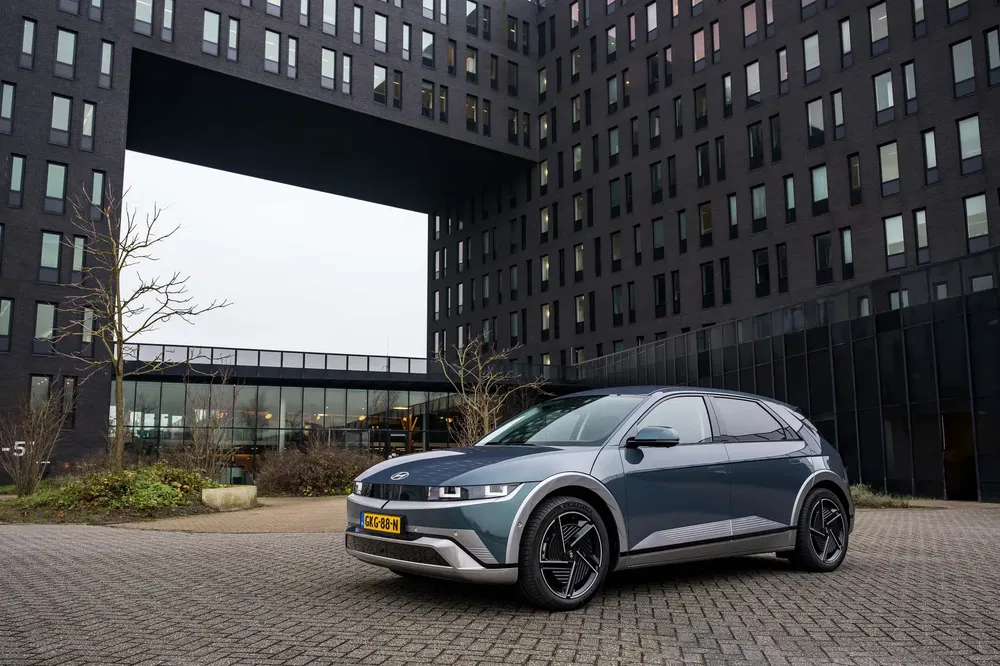 Hyundai Ioniq 5 moderne stationnée devant un immeuble noir imposant.