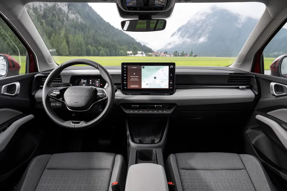 Intérieur d'une Skoda avec tableau de bord numérique et vue sur montagnes.