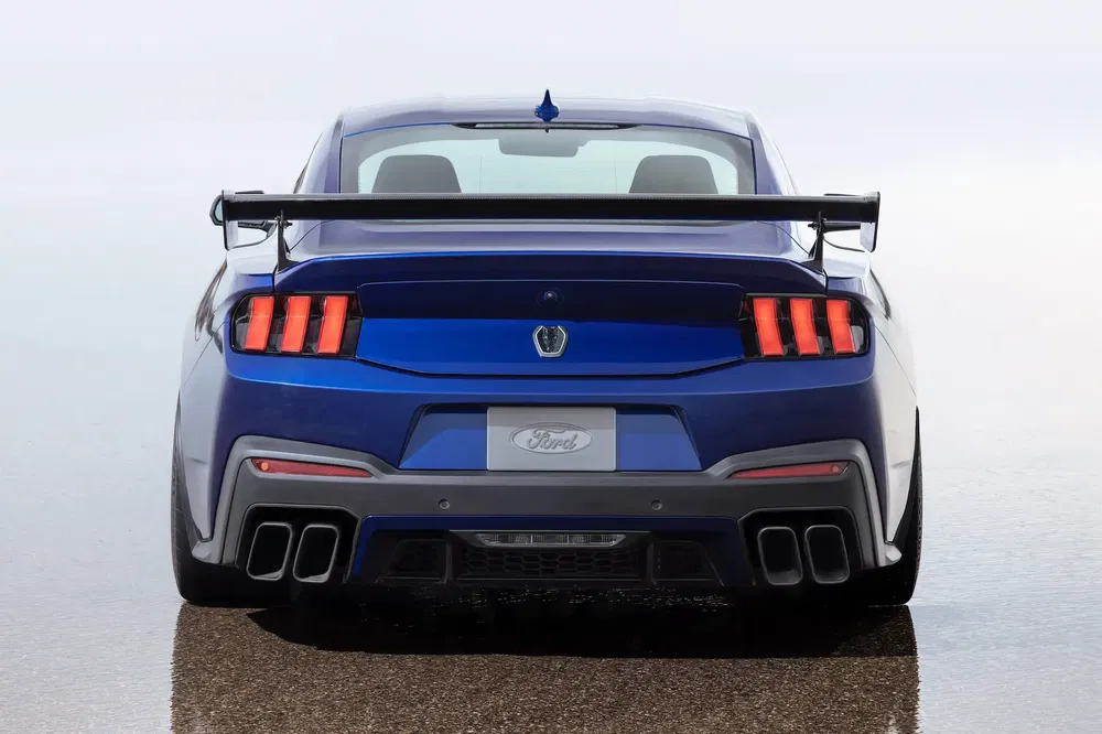 Arrière d'une Ford Mustang bleue, aileron proéminent, quatre sorties d'échappement.