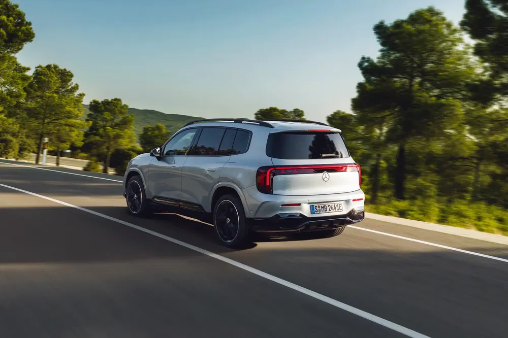 SUV Mercedes-Benz blanc sur route, entouré de forêt verdoyante.