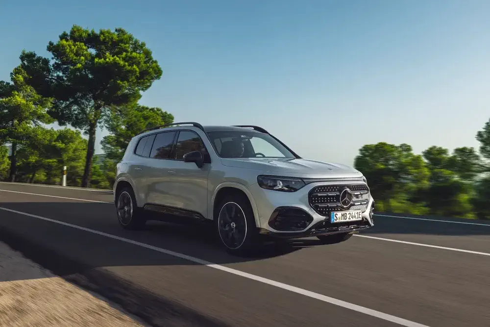 SUV Mercedes-Benz GLB roulant sur une route bordée d'arbres par temps clair.