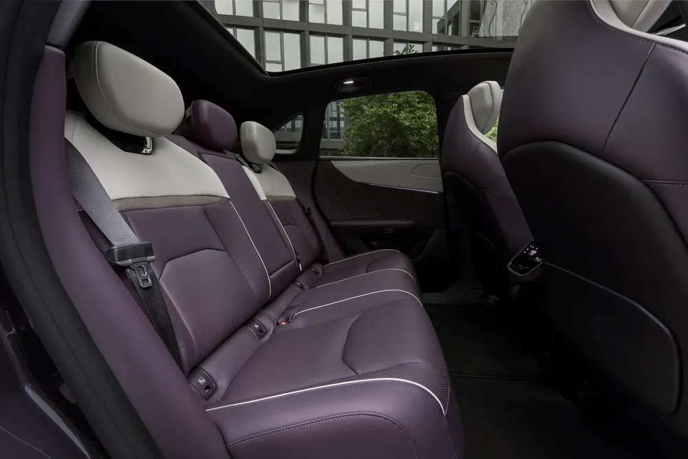 Intérieur de voiture moderne, sièges arrière en cuir violet avec appuie-tête blancs, design élégant.