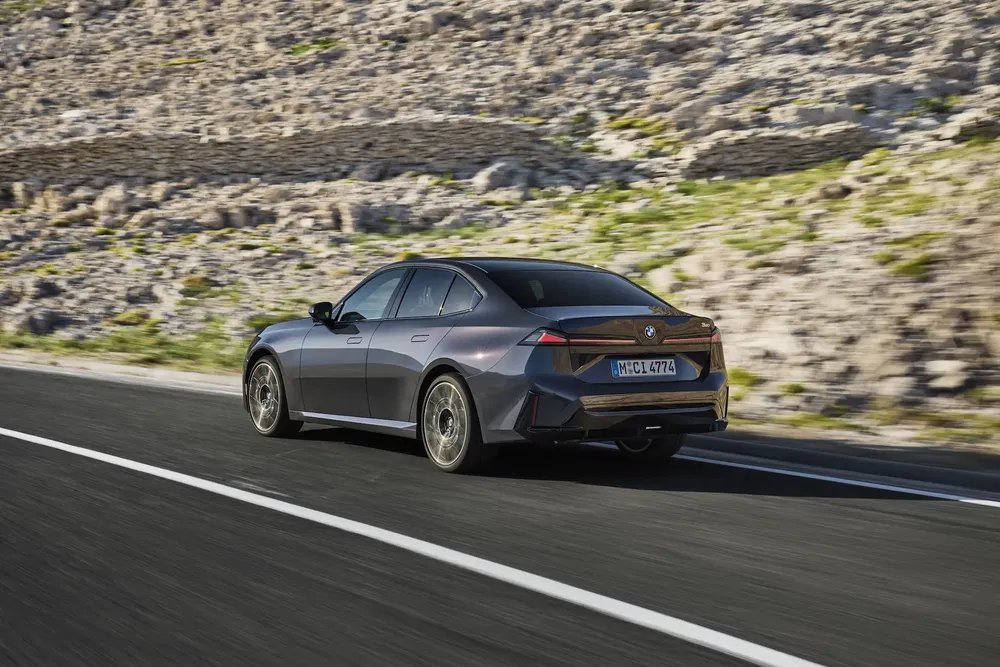 BMW i5 en mouvement sur une route montagneuse, design élégant et dynamique.