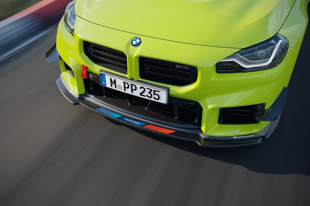 Groene BMW M2 met Duitse kentekenplaat, racend op circuit.