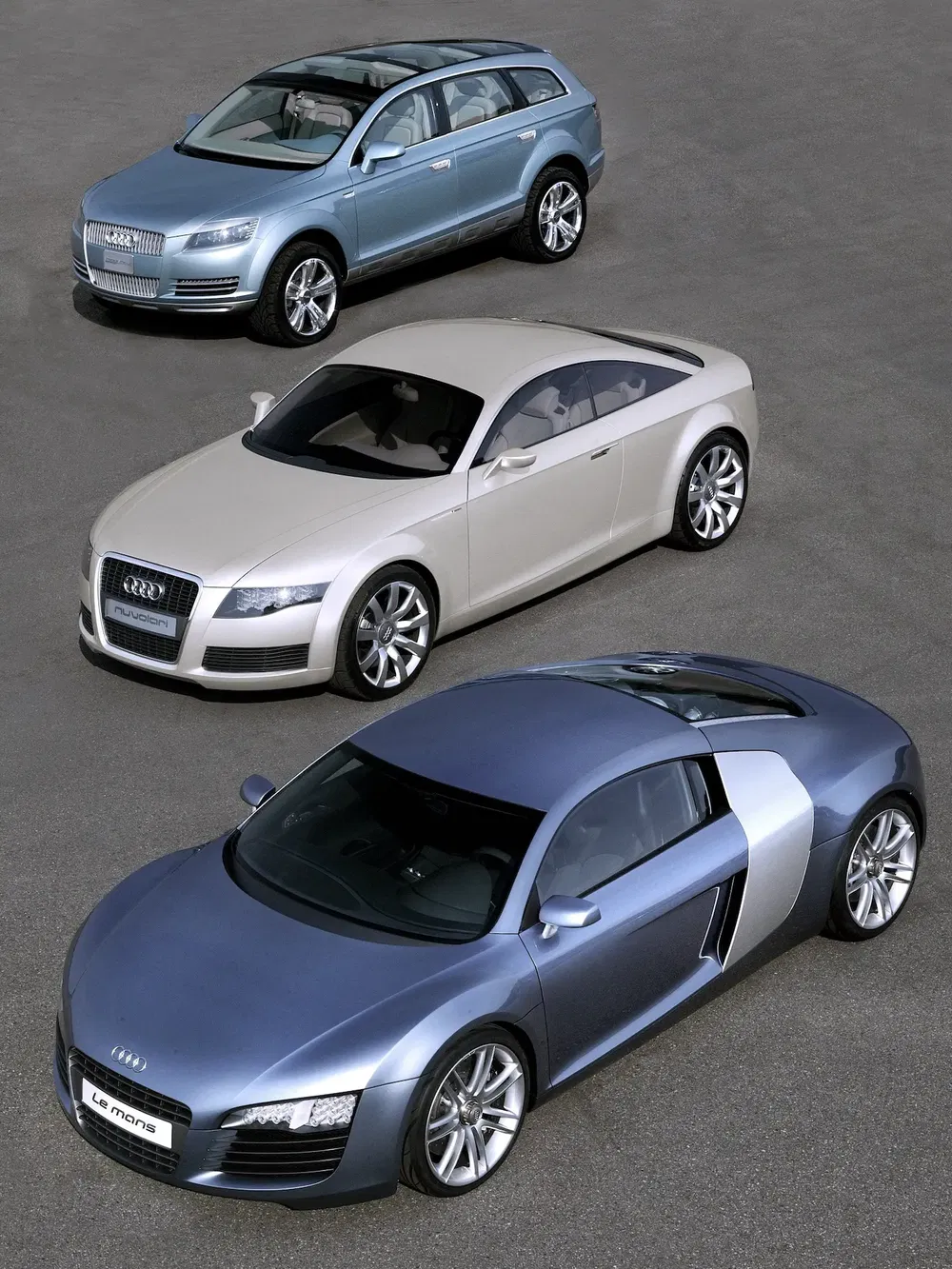 Trois modèles Audi alignés : Q7, TT et Le Mans Quattro, sur un fond gris.