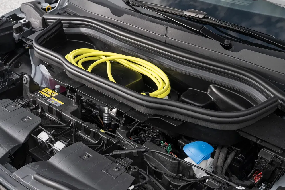 Compartiment avant d'une voiture électrique avec câble de charge jaune enroulé.