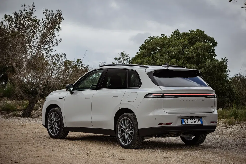 Witte Leapmotor C11 SUV geparkeerd op landelijke weg met bewolkte lucht op de achtergrond.