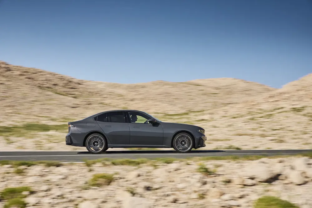 Volvo électrique Polestar 2 roulant dans un désert sous un ciel bleu éclatant.