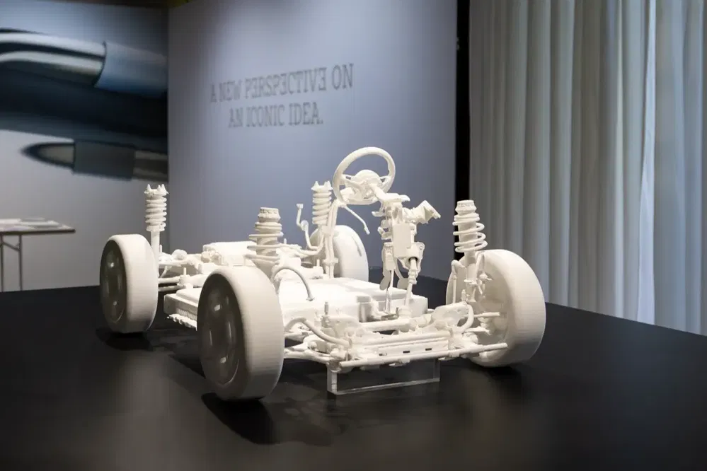 Châssis imprimé en 3D avec suspension visible sur table d'exposition automobile.