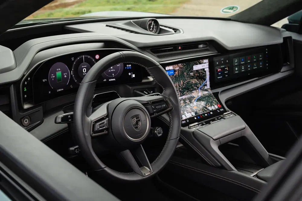 Intérieur moderne d'une Porsche, affichage numérique, volant ergonomique, écran GPS central visible.