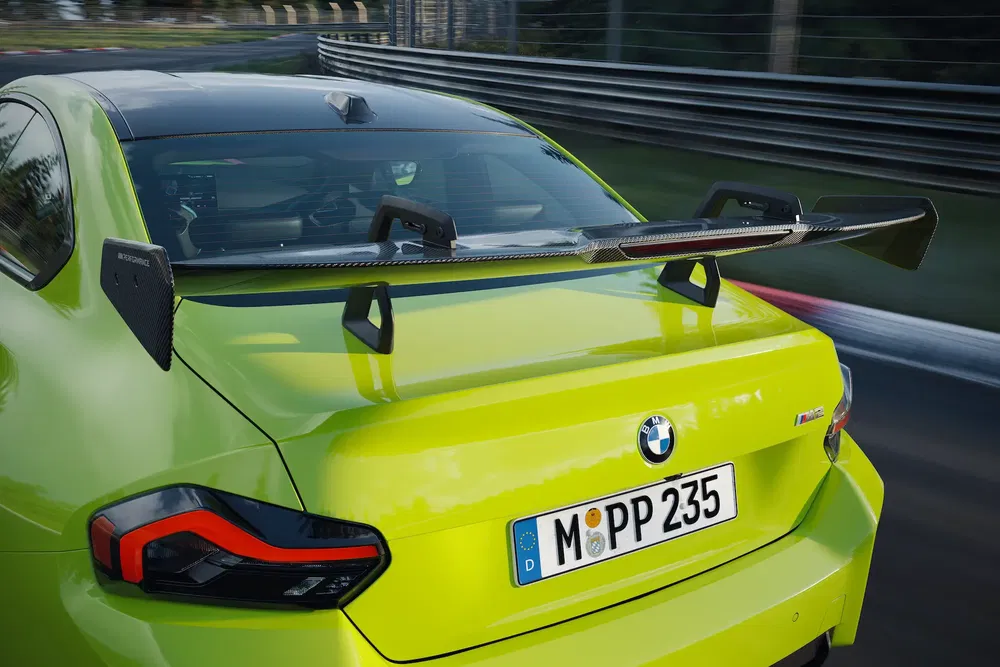 Heldere groene BMW M4 met spoiler op racecircuit.