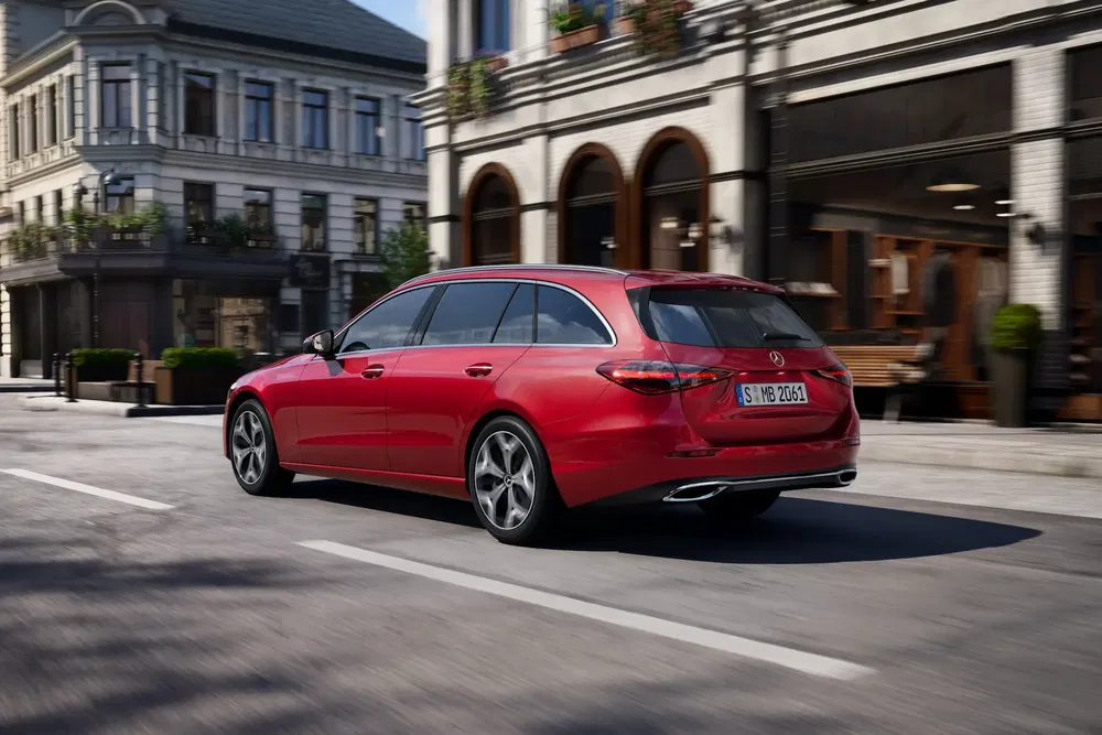 Mercedes rouge break roulant dans une rue de ville, design élégant et moderne.