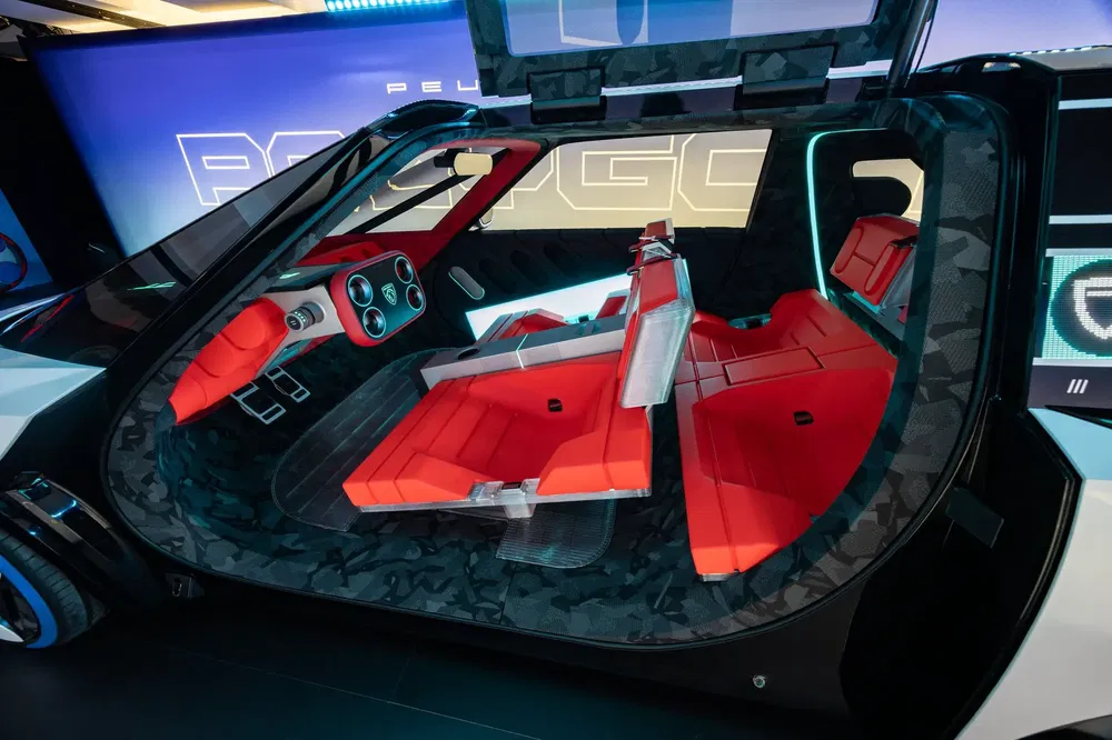 Intérieur futuriste d'un concept car Peugeot avec sièges rouges et tableau de bord high-tech.