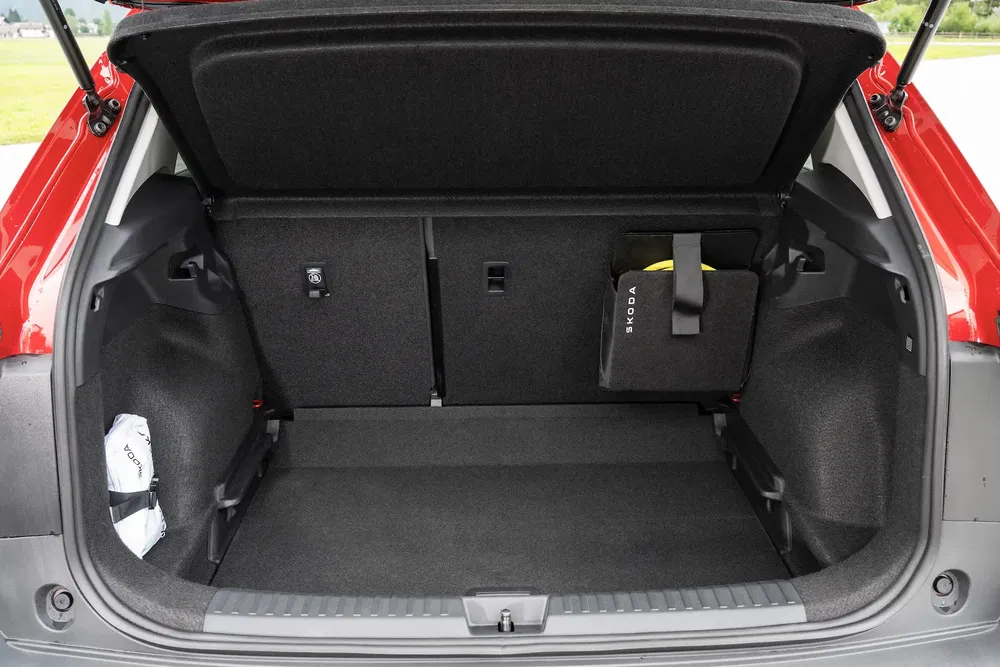Coffre spacieux d'une Skoda rouge avec compartiment de rangement intégré.
