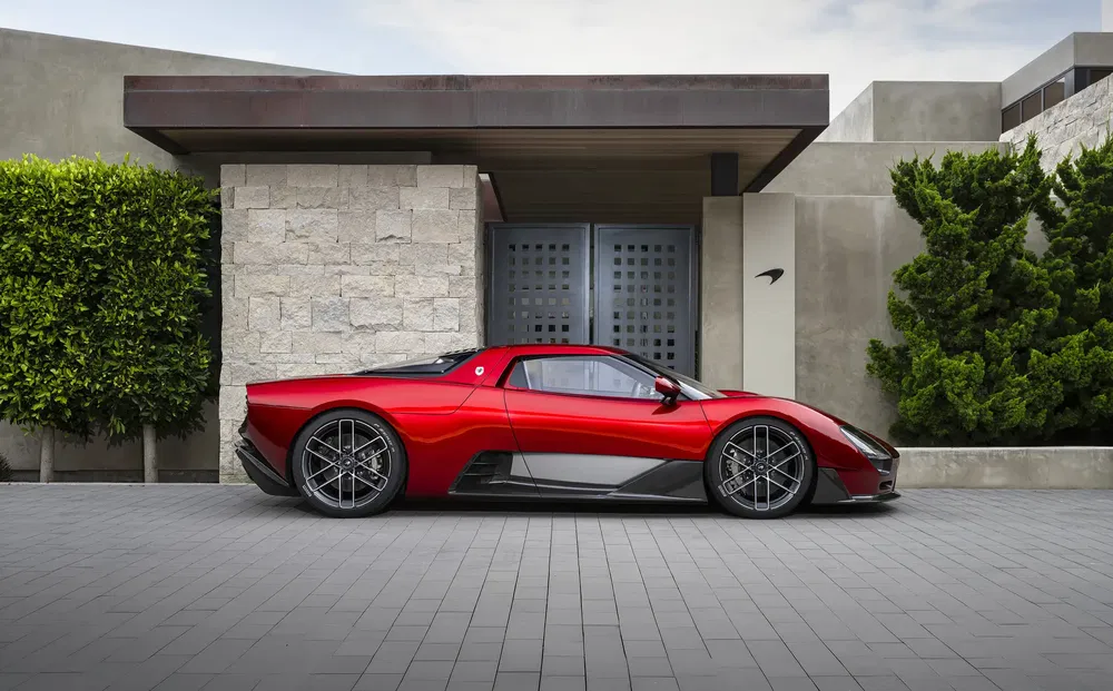 Rode Ares S1 Project supercar geparkeerd voor een moderne stenen woning.