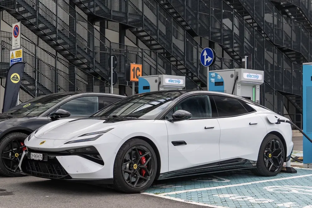 Lotus électrique moderne stationnée à une borne de recharge, design futuriste et sport.