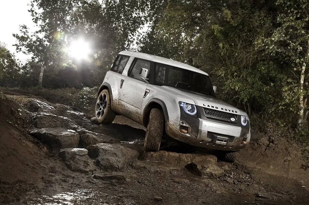 Land Rover Defender in ruig terrein, toont offroad-capaciteiten.