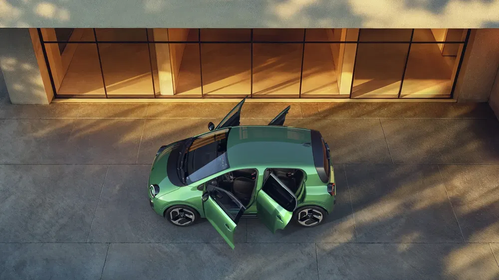 Volkswagen ID.3 verte avec portes ouvertes devant un bâtiment moderne en verre.
