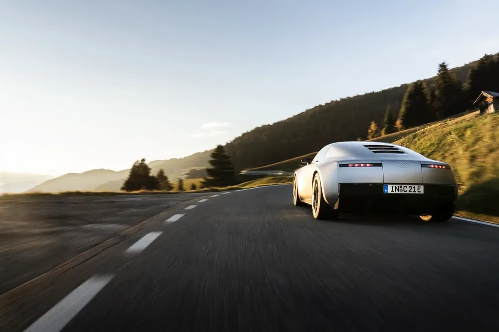 Audi concept sportive roulant sur route de montagne sinueuse au coucher du soleil.