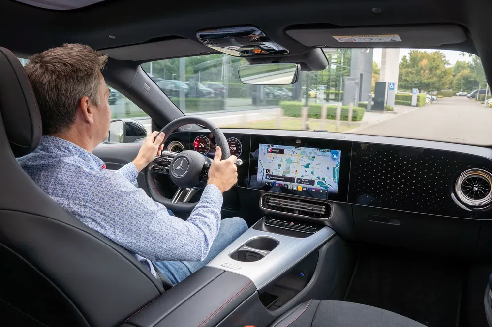 Intérieur de la Mercedes-Benz avec écran GPS moderne et conducteur concentré sur la route.