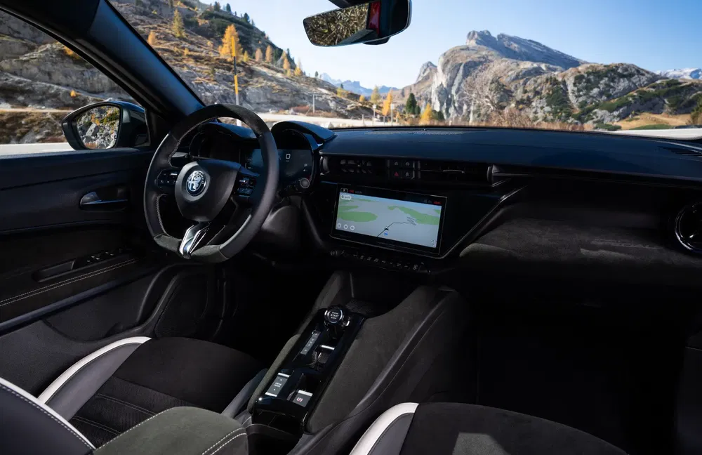Intérieur de voiture Alfa Romeo moderne avec écran tactile et vue sur montagnes pittoresques.