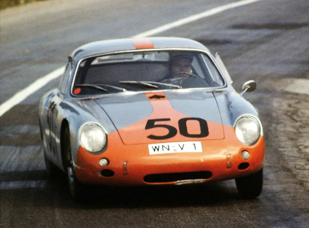 Voiture de course Porsche avec numéro 50 sur une piste sinueuse.