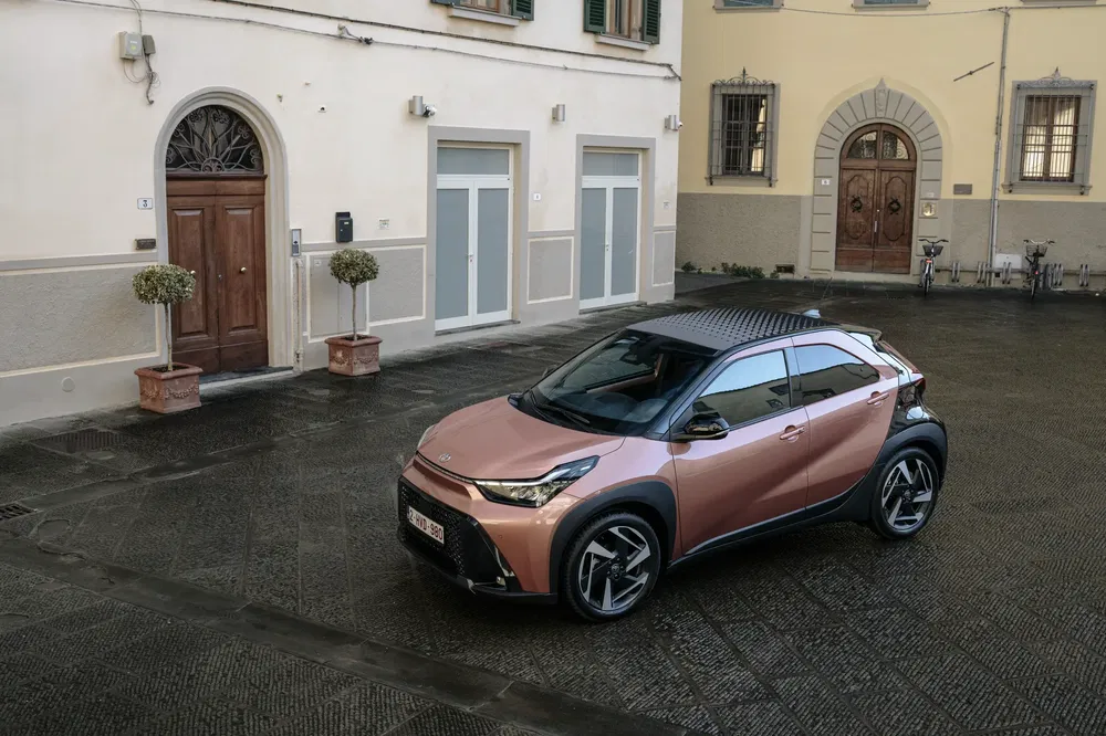 Toyota crossover moderne stationné dans une cour pavée sous un ciel clair.